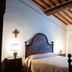 Agriturismo Villa La Morina bedroom in Cortona with wrought-iron bed, wooden beams and open window