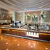 Hilton Colon Guayaquil buffet restaurant with central island, floral arrangements, and warm wood flooring