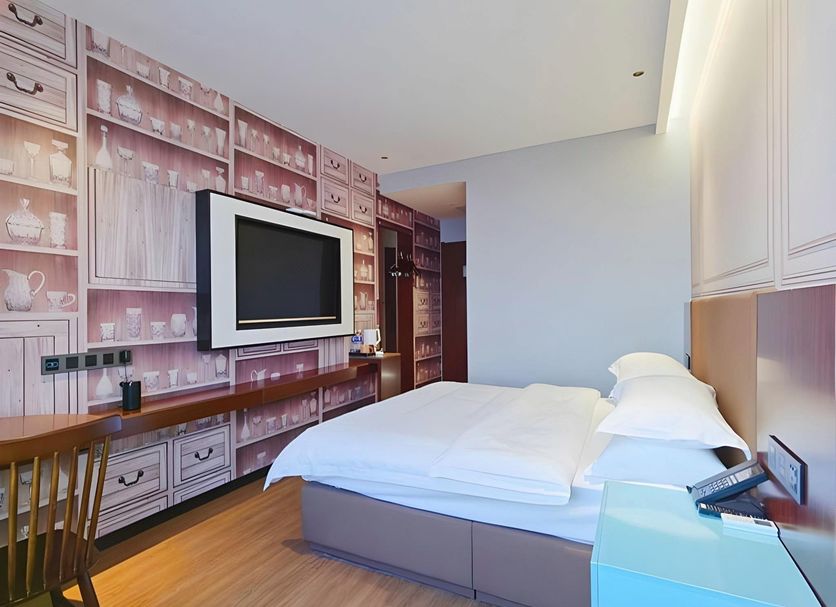 Guest room at Gem Hotel Nanjing Dachang Xinhua Road Pedestrian Street with wall-mounted TV and bed