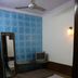 Yes Please Guest House New Delhi simple guest room with single bed, wall fan, TV and patterned blue accent wall