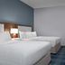 Hampton Inn Russellville guest room with two beds, desk, wall-mounted TV and teal chair