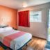 Motel 6 Mammoth Lakes room with queen bed, orange accent wall, desk, window and patio door