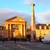 C'est une maison bleue in Bordeaux with a city street view of the historic stone gateway and column.