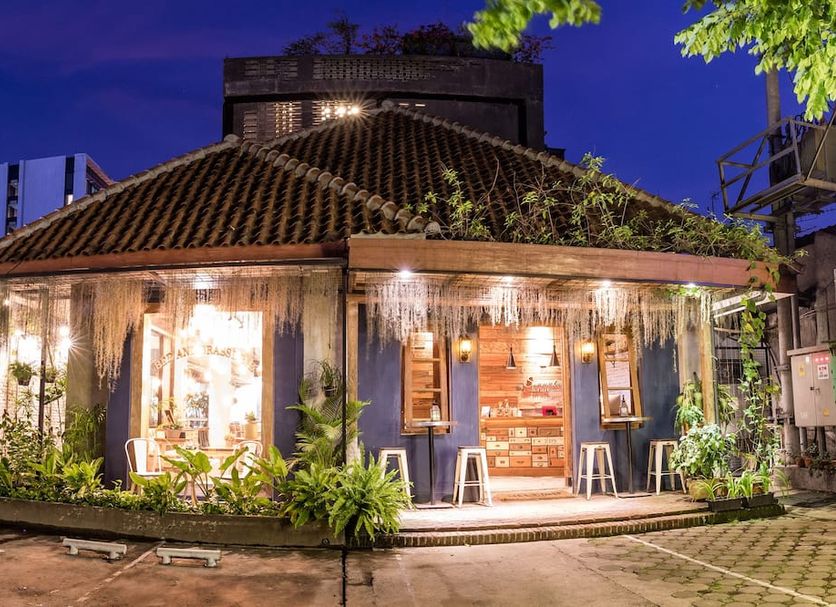 Summerbird - Bed and Brasserie in Bandung, lit hotel building with tiled roof and tropical plants at night
