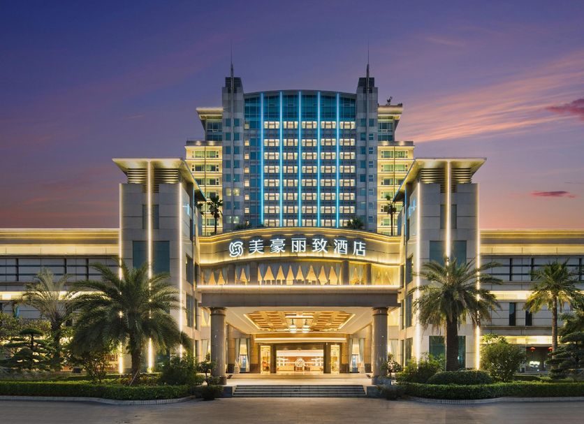 Dongguan Huaxi International Hotel exterior at dusk with illuminated entrance and palm trees in Dongguan