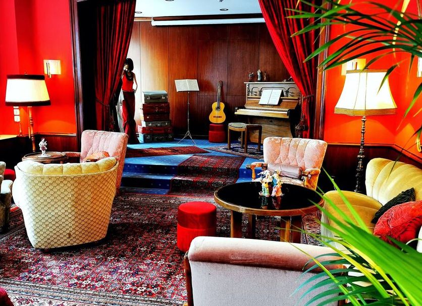 Wohnen Bei Tante Alma Mannheim lounge with red walls, armchairs, piano, guitar and stage area