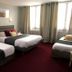Hotel Le Canada in Hermanville-sur-Mer guest room with three beds, curtains, and a burgundy carpet