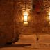 Olea Leya Hotel Ayvalik bedroom with stone wall, warm sconces, and neatly made bed