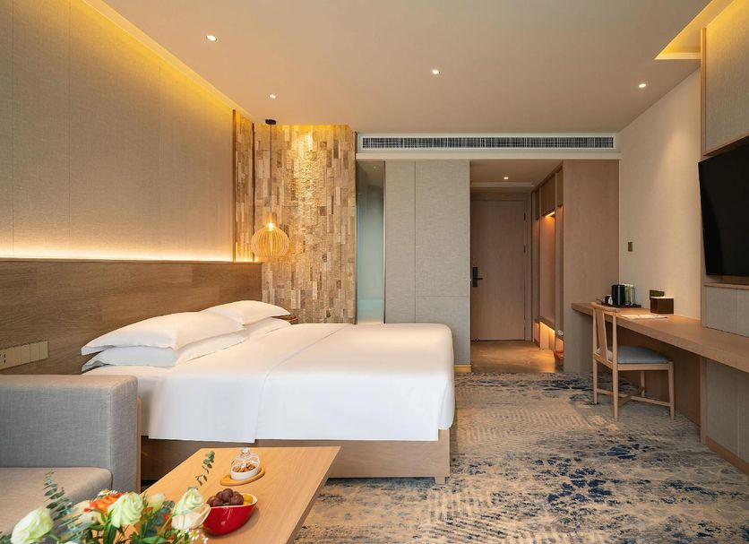 Expo Garden Resort Hotel Jinan room with king bed, desk, wall-mounted TV and warm lighting