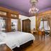 Patterson Inn Denver guest room with king bed, chandelier, wood floors, desk, and wall-mounted TV