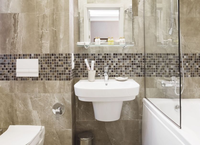 Roxen Hotel&Spa in Chisinau bathroom with bathtub, sink, wall mirror, and mosaic tile accent