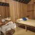 La Villa Creole, Pondicherry: simple wood-paneled guest room with bed, chair, mirror and window curtain