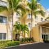 Homewood Suites by Hilton Bonita Springs Naples North exterior with palm trees and covered entrance in Bonita Springs