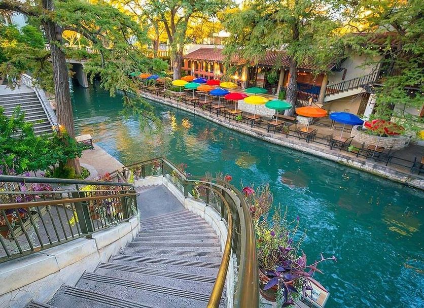 Candlewood Suites Kenedy By IHG canal-side stairway with colorful umbrellas and riverside seating