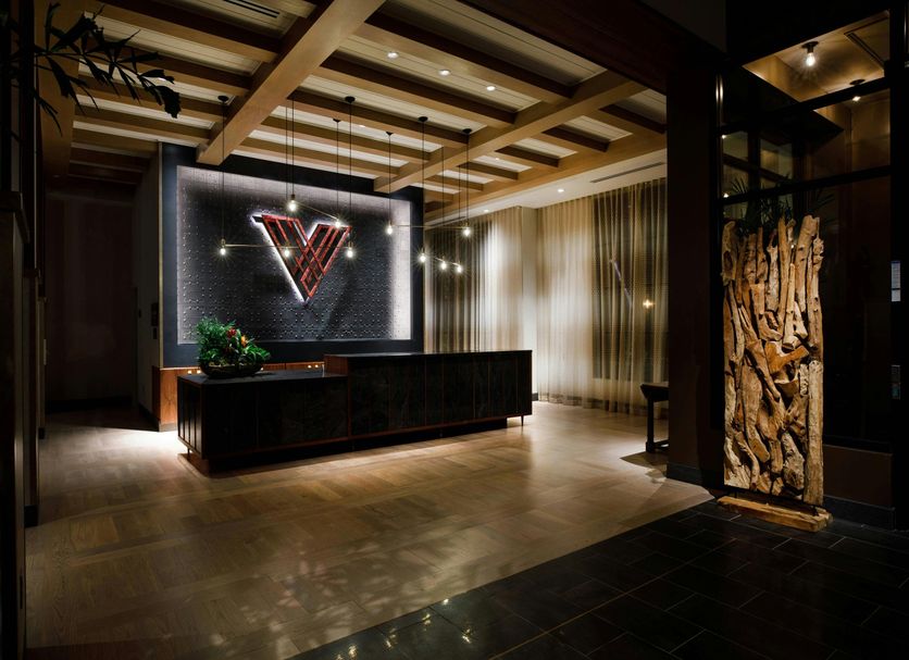 Hotel Vin, Grapevine, Autograph Collection lobby with illuminated V logo, wood ceiling beams and reception desk