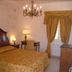 Masseria Magli Resort in Martina Franca bedroom with ornate bed, chandelier, table lamps and draped window