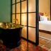 Stamba Hotel in Tbilisi: stylish bathroom with gold freestanding tub beside a bedroom with city view