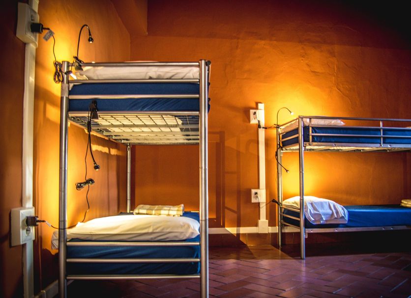 Hostel Santa Monaca in Florence with two blue metal bunk beds in a warm-lit shared room