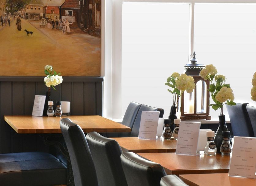 Fletcher Badhotel Egmond aan Zee dining room with wooden tables, black chairs, and seaside mural