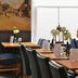 Fletcher Badhotel Egmond aan Zee dining room with wooden tables, black chairs, and seaside mural