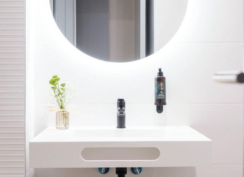 Hotel Cisneros in Alcalá de Henares bathroom vanity with round mirror, sink, and towels