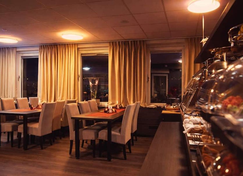Liljeholmens Stadshotell in Stockholm dining room with set tables, beige chairs, and warm evening lighting