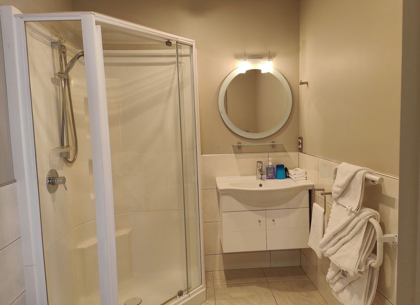 Athena Motel Christchurch bathroom with walk-in shower, vanity, and wall mirror