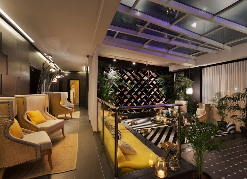 Brown Beach House Tel-Aviv lounge with glass railing, yellow seating, plants and patterned terrace