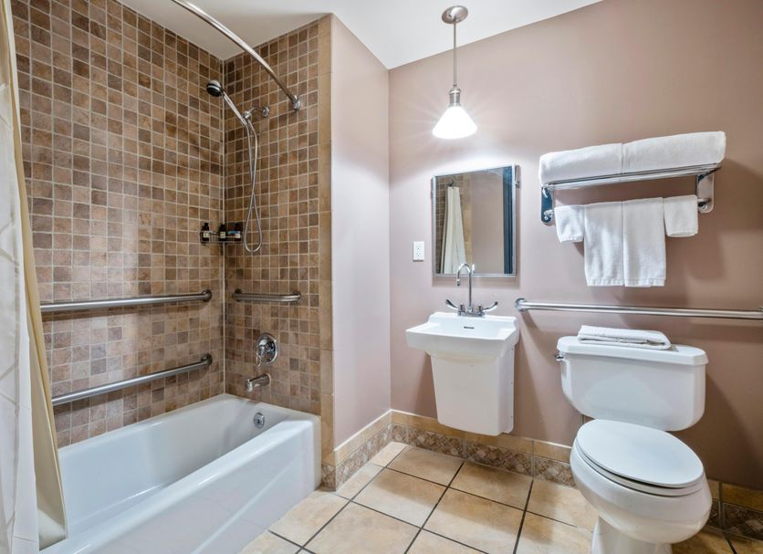 The Harbor Front Inn Greenport bathroom with tub-shower, pedestal sink, and toilet