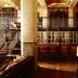 Hotel Emma San Antonio lobby with tall columns, twin staircases, bar seating and warm industrial design