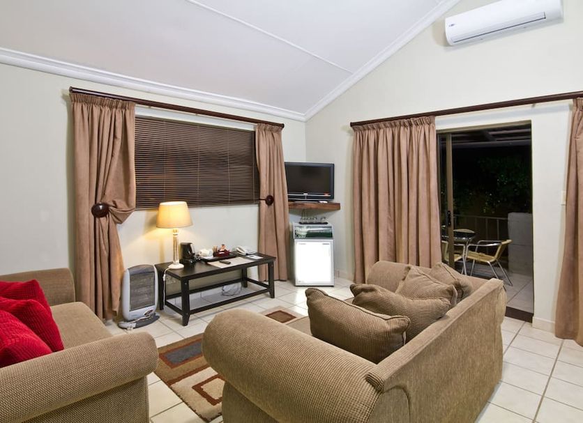 Anew Resort White River Mbombela living room with sofa, TV, table lamp and patio doorway to outdoor seating