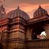 Hotel Pooja International, Nashik: temple-style building at sunset with domed towers and carved stone exterior