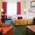 Holiday Inn Express & Suites Brooksville West guest room with king bed, sofa, desk and window seating