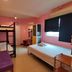 Urban Hostel Bangkok room with bunk bed, twin bed, desk, and blacked-out window in pink walls