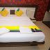 Hotel Naivedya, Aurangabad: neatly made double bed with colorful pillows and folded towels on the bed