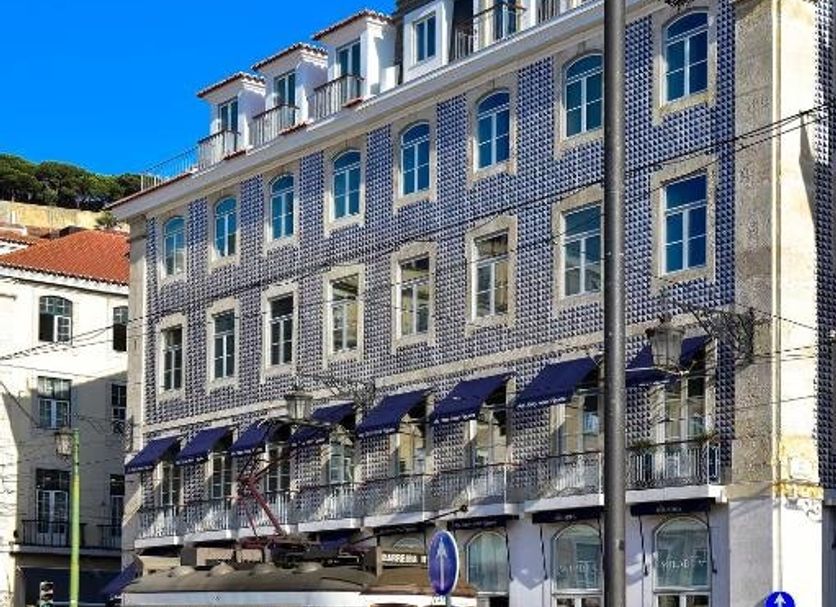 My Story Hotel Figueira in Lisbon, historic facade beside a yellow tram on a city street