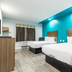 Scottish Inns & Suites - Kingwood in Humble: two beds in a bright room with teal accent wall