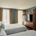 Emeline Charleston guest room with two beds, TV cabinet and sitting area