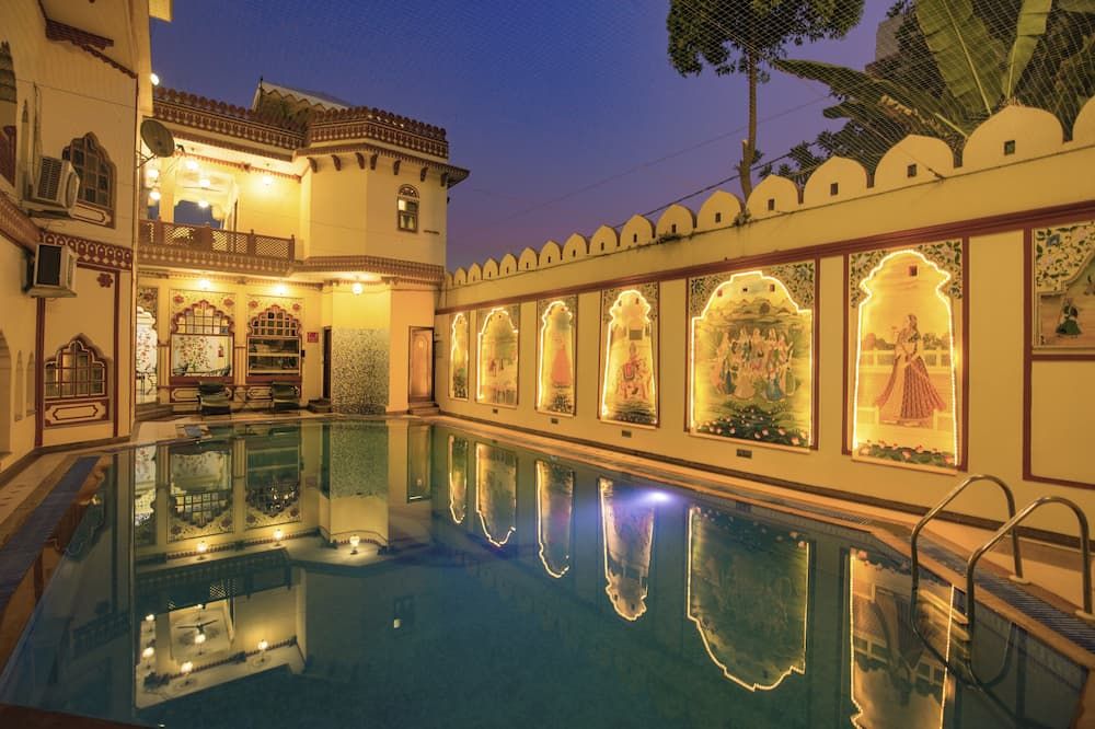 Umaid Bhawan - A Heritage Style Boutique Hotel in Jaipur with illuminated courtyard pool and arched murals