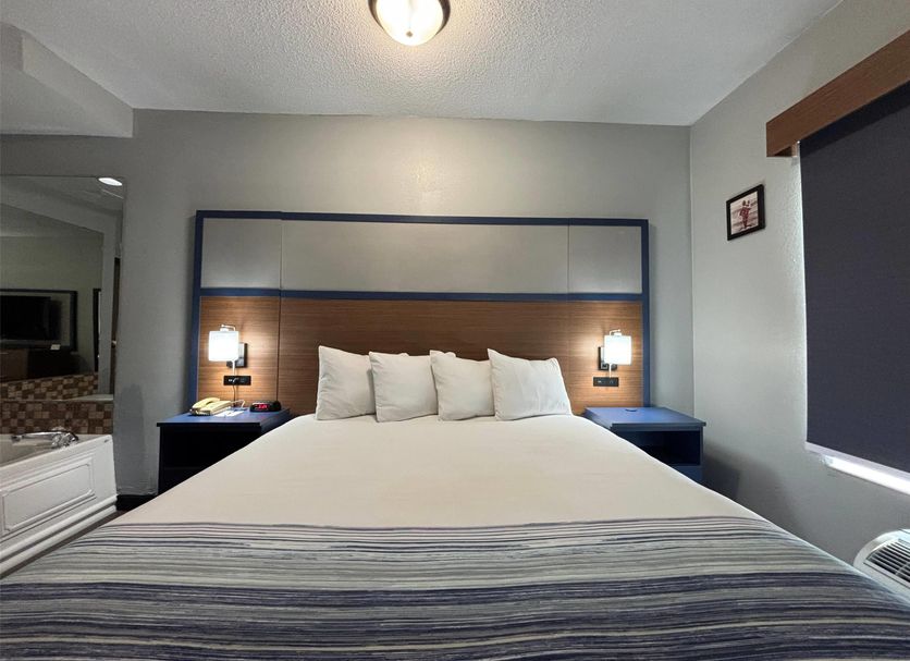AmericInn by Wyndham Galesburg guest room with king bed and bedside lamps