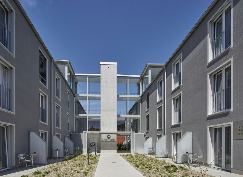 Aparthotel Baden courtyard with modern gray buildings and central glass walkway in Baden
