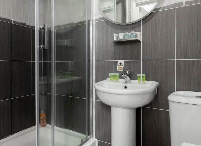 Orlando hotel London bathroom with glass shower, pedestal sink and toilet