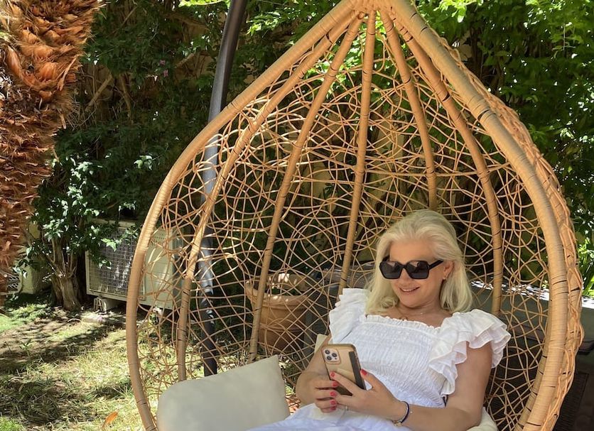 Hotel Jardin Croisette in Cannes: woman relaxing in woven hanging chair amid lush garden greenery