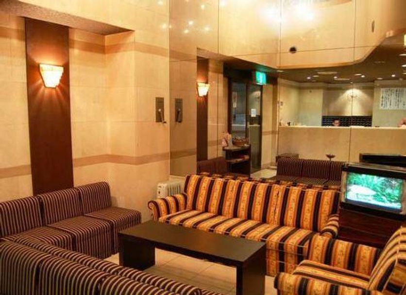 Hiroshima Ekimae Green Hotel lounge in Hiroshima with striped sofas, coffee table and TV