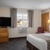 Super 8 by Wyndham Lewistown guest room with king bed, TV, window, and wall AC unit