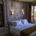 Olea Leya Hotel in Ayvalik bedroom with stone walls, double bed, and balcony doors