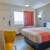 Motel 6 Santa Rosa Nm guest room with queen bed, window view, and a yellow chair in Santa Rosa