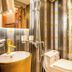 Mai Hotel Hanoi bathroom with gold sink, toilet, shower and bamboo garden-style wall