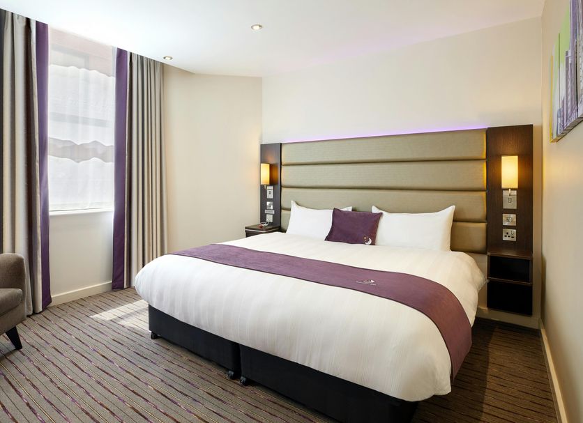 Premier Inn Norwich Airport bedroom in Norwich with a double bed, tall windows and striped carpet
