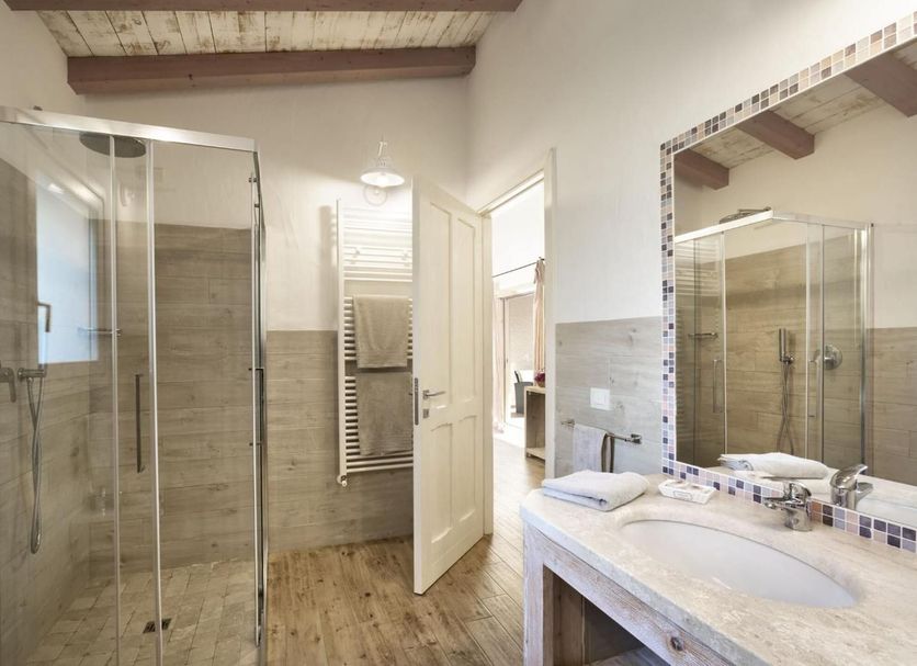 Tenuta Pilastru in Arzachena: modern bathroom with glass shower, vanity, and wood-beam ceiling